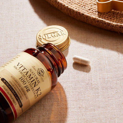 Solgar Vitamin K2 100 mcg supplement in 50 vegetable capsules, displayed in a clear container with label details.