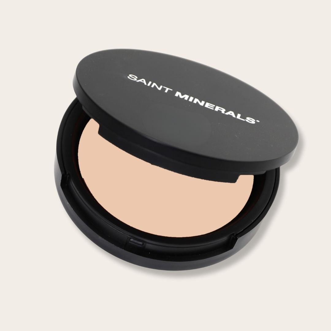 Pressed powder foundation by Saint Minerals in warm shade, showing a compact with smooth, finely milled makeup product.