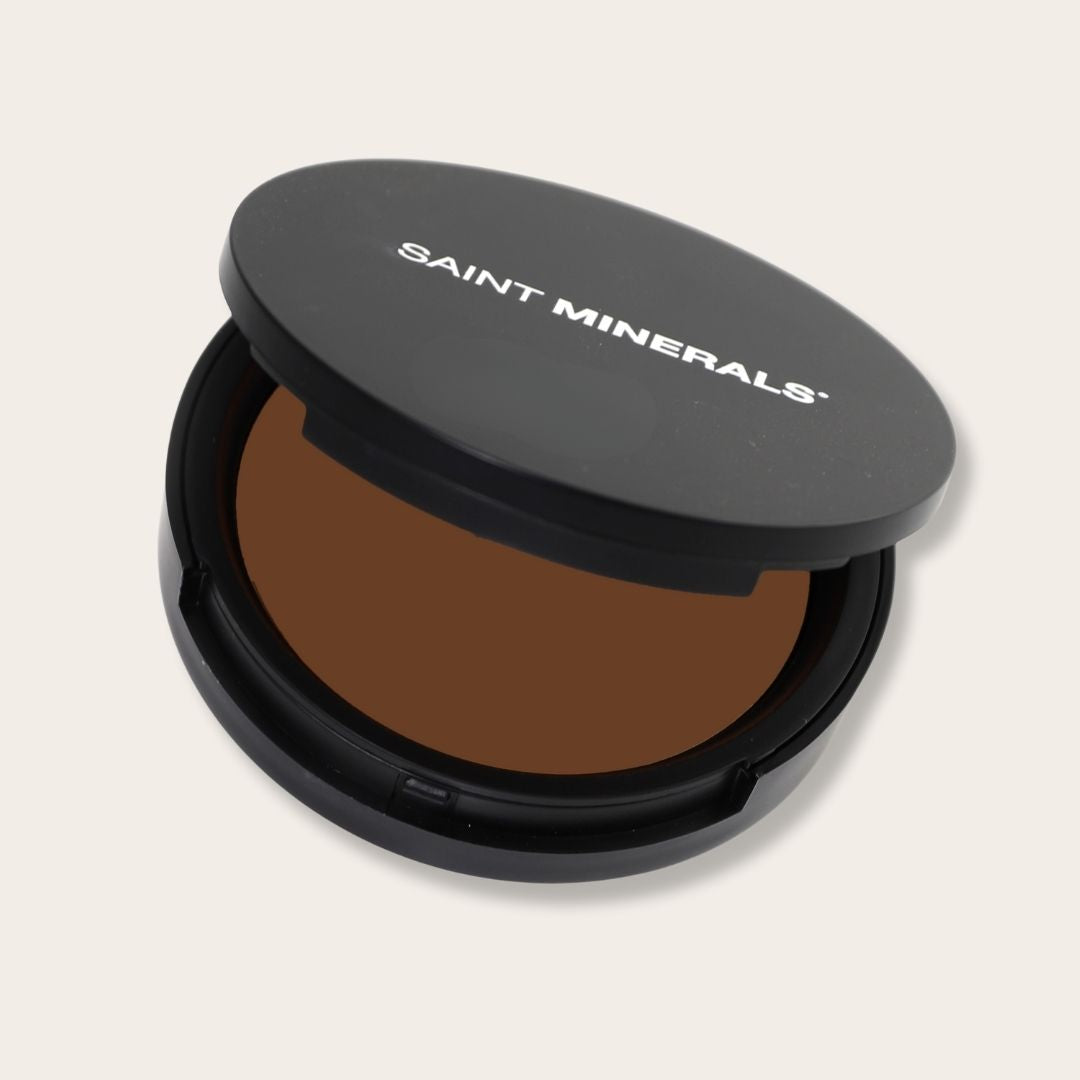 Pressed powder foundation by Saint Minerals with warm tones, showcasing smooth, finely milled makeup in natural light.