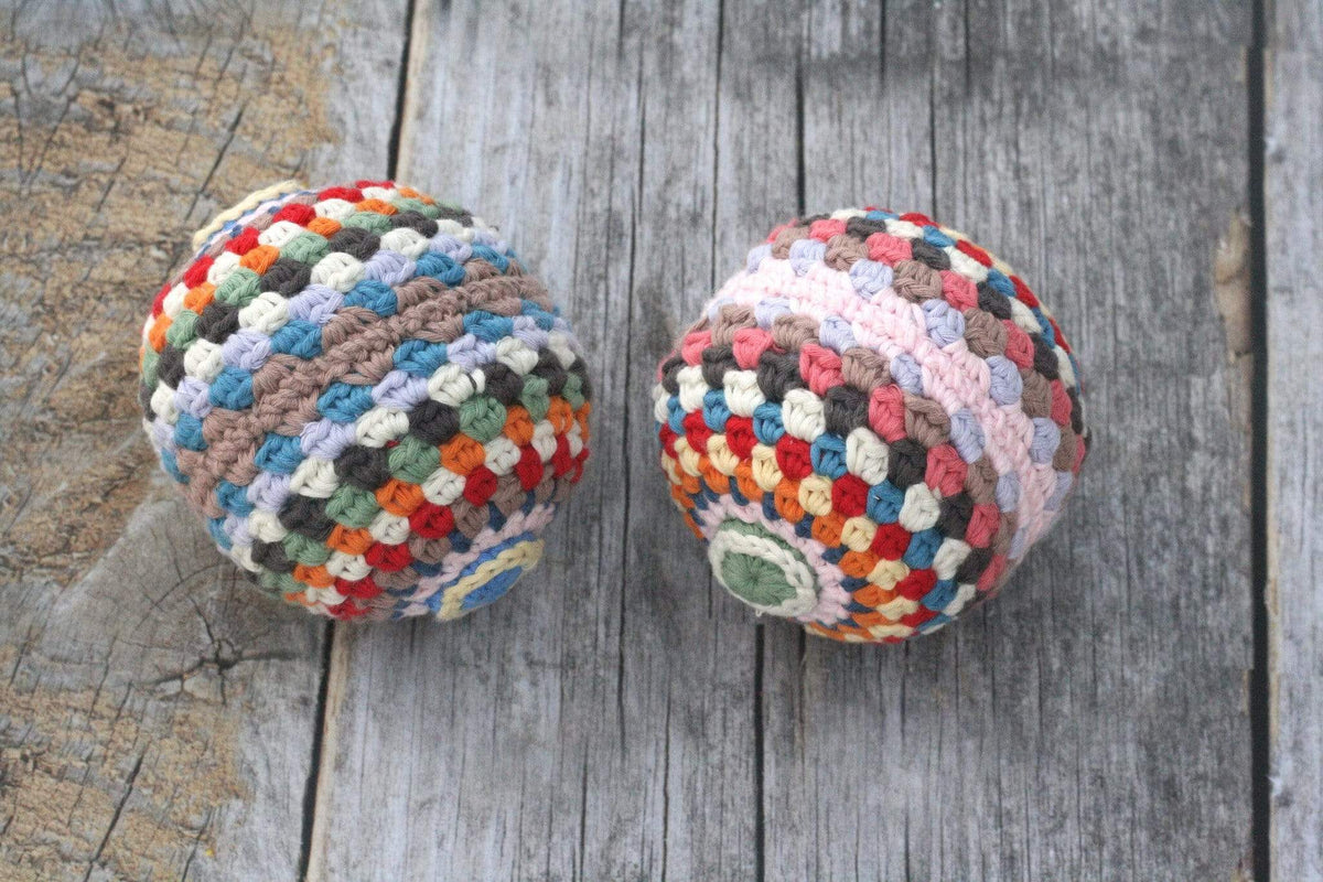 Colorful rainbow rattle ball toy made of organic cotton, featuring vibrant stripes and a handheld design for infants.