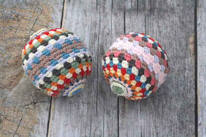 Colorful rainbow rattle ball toy made of organic cotton, featuring vibrant stripes and a handheld design for infants.