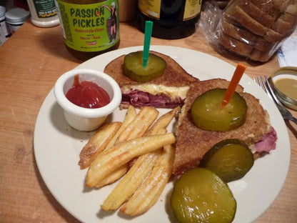 Reuben sandwich with Passion Pickles® Ghost Pepper Homestyle Chips on a plate, showcasing spicy pickle slices and crispy bread.
