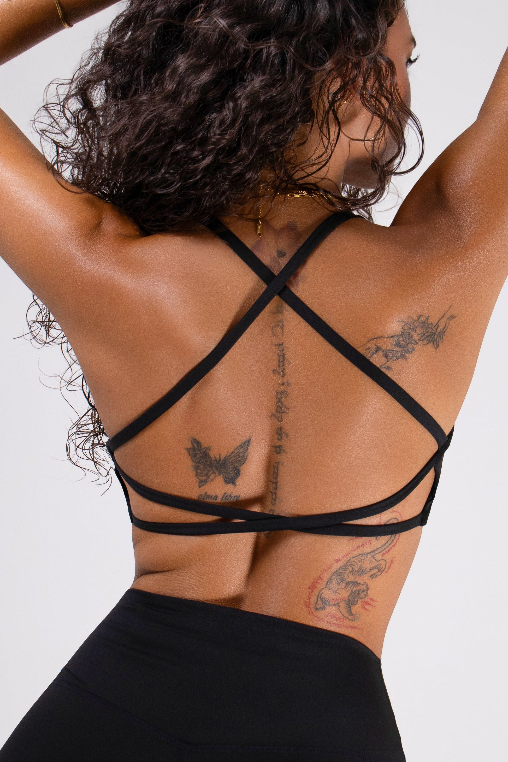 Black women's open-back sports bra with strappy design and scoop neckline, providing medium support by Runner's Athletics.