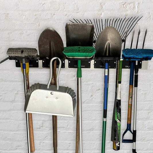 TRAPSKI garage wall rack organizer holding yard tools, gear, skis, and snowboard bindings for efficient storage.