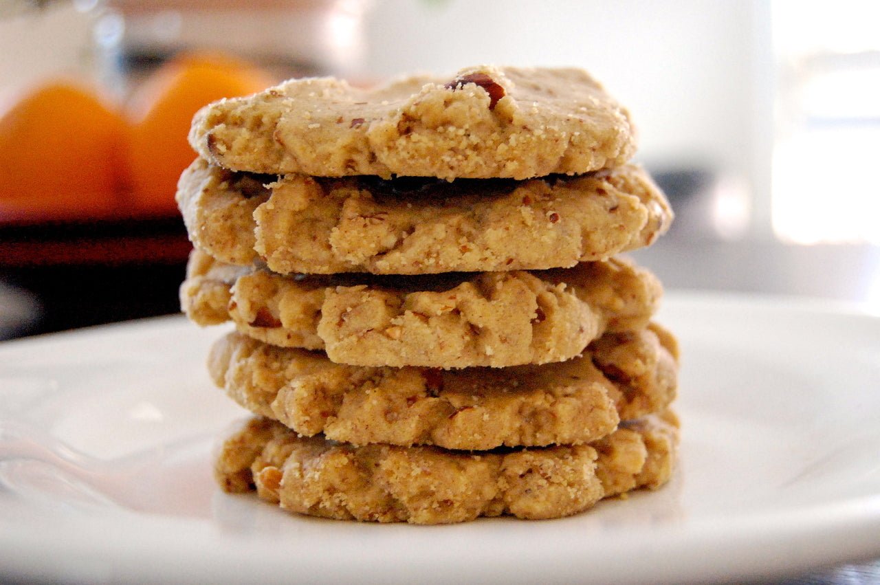 Vegin' Out Extra Vegan Cookies, soft and chewy plant-based cookies on a white plate with a glass of juice in the background.