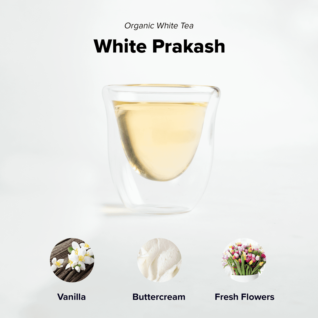 Organic White Prakash tea by Nepal Tea featuring white tea leaves in a clear glass cup on a wooden surface.